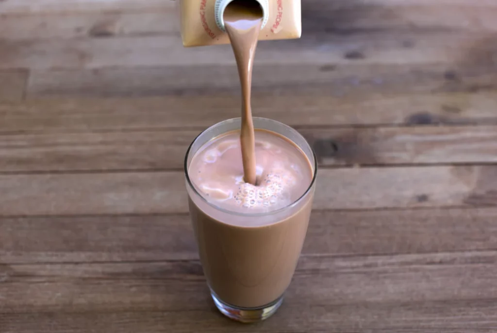 Lattini chocolate sunflower milk being poured into a glass on a table